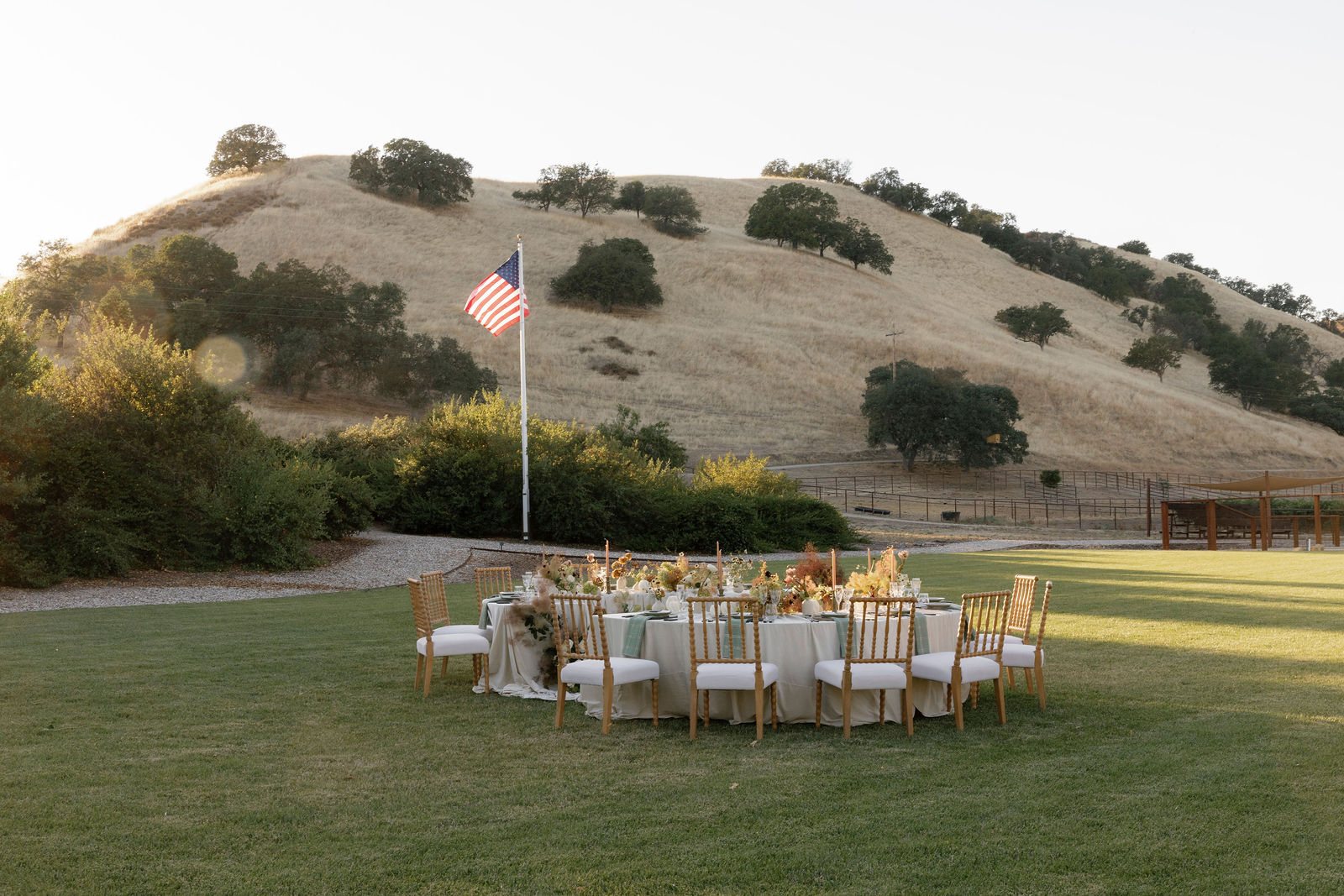 Round dinner tables set on the lawn beneath the hills