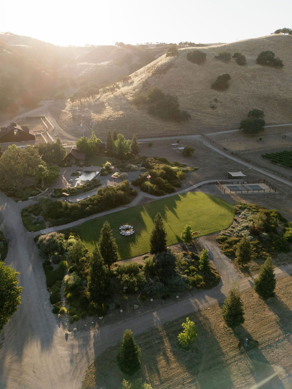 Aerial view of the ranch estate, lawn, and pool among oak-covered hills