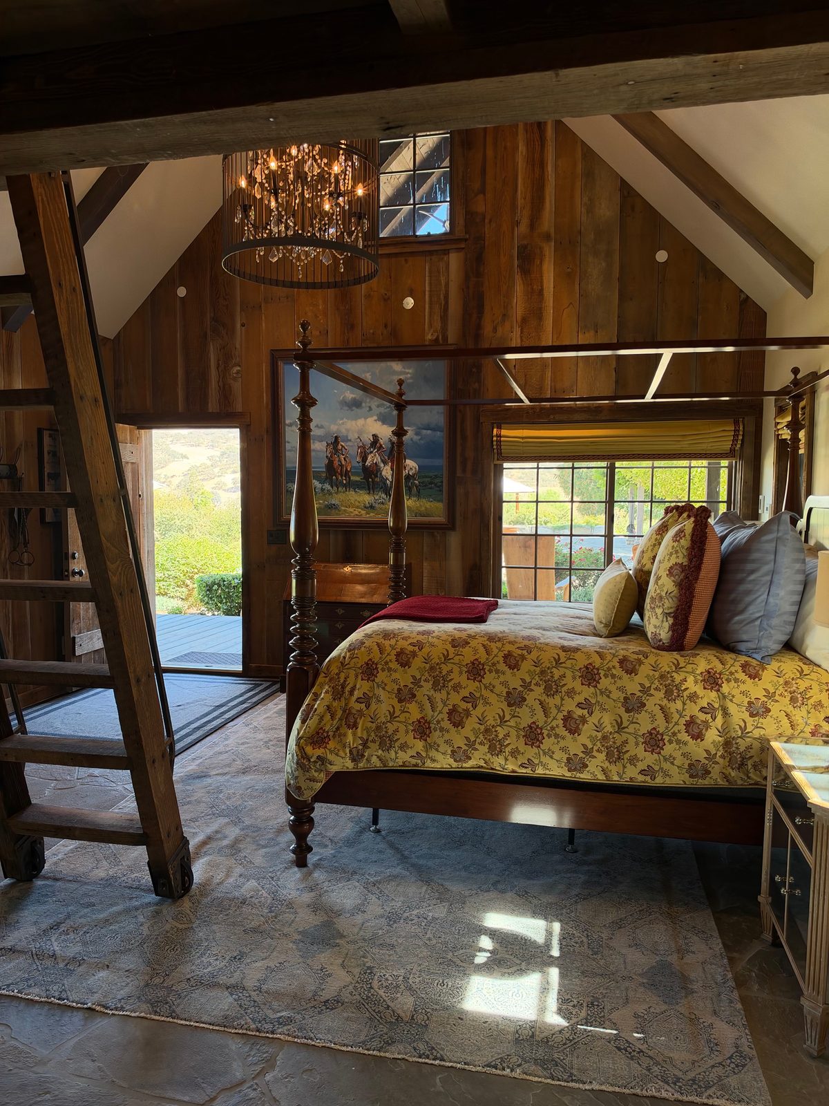 A beamed guest room with a ladder to the loft